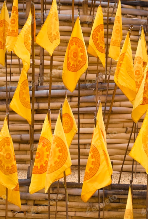 Preview: Yellow prayer flags stuck in sand at a wat temple.