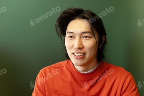 Preview: Young Asian Man Smiling and Looking Away on Green Background