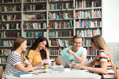Preview: Young people discussing group project at table in library