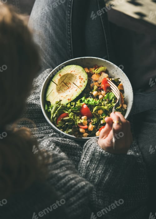 Preview: Woman eating healthy vegetarian dinner from Buddha bowl, top view