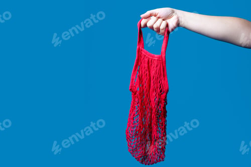 Preview: Human hands studio shot on blue background holding eco and plastic free net bags