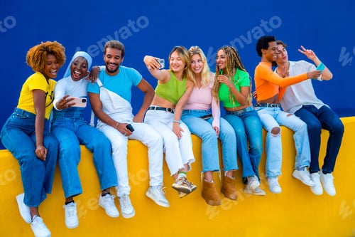 Preview: Multi-ethnic friends sitting on an urban wall and taking selfies