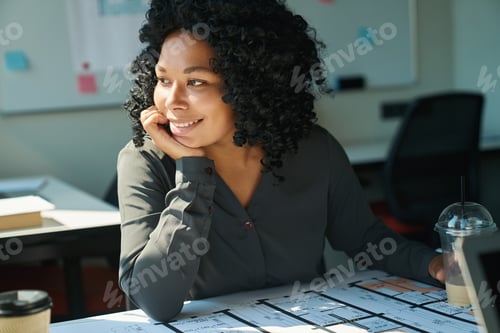 Preview: Multiracial designer female looking out the window with dreamy smile