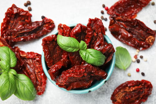Preview: Delicious sun dried tomatoes in bowl and spices on gray table, flat lay