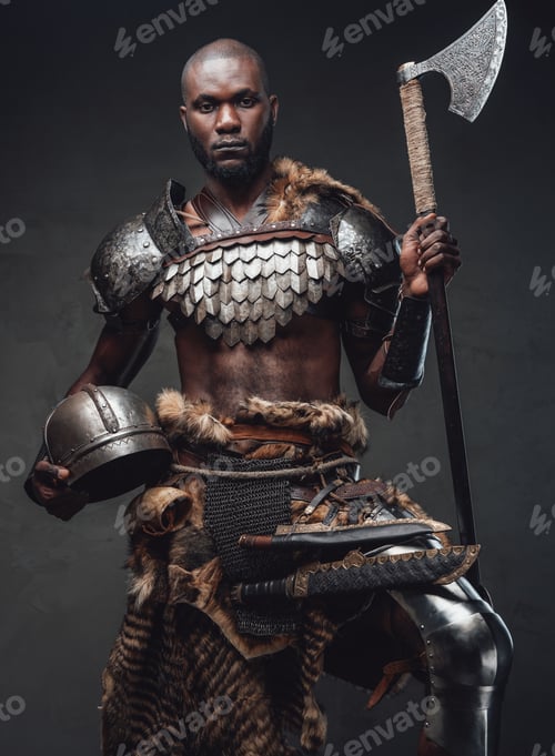 Preview: Brave african soldier from the past looking at camera holding an axe