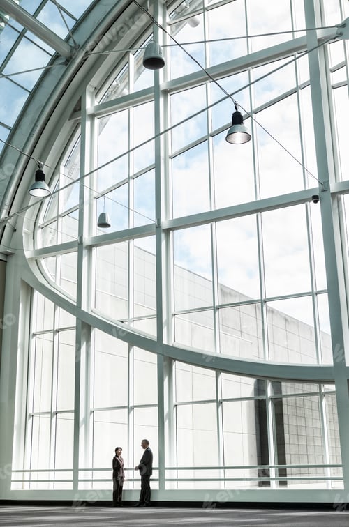 Preview: Businessman and woman meeting in a large glass covered walkway