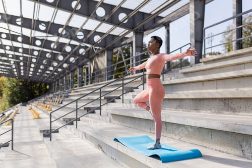 Preview: African American woman doing yoga near the stadium in the morning