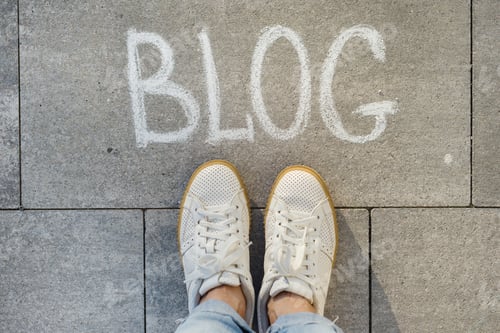 Preview: View from above, female feet with text blog written on grey sidewalk