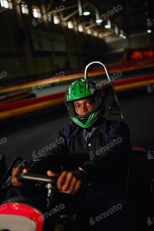 Preview: african american go kart driver in helmet driving on indoor circuit, speed racing track, motorsport