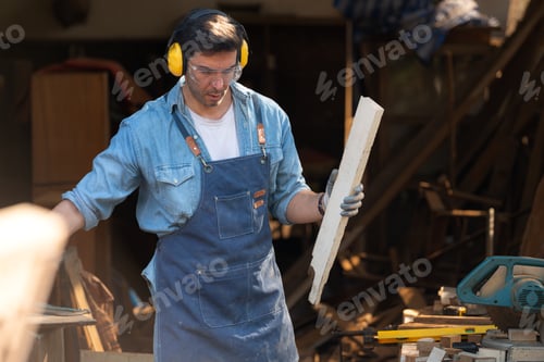 Preview: Portrait of a carpenter holding a spirit level in his workshop.