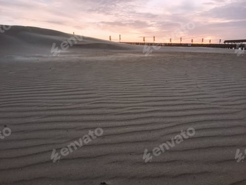 Preview: Sandy Beach at Sunrise with Distant Pier