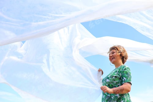 Preview: The girl develops a white cloth across the blue sky. Air
