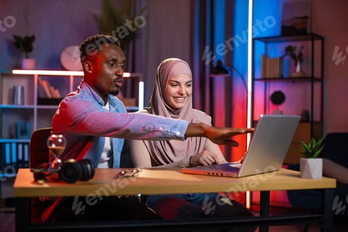 Preview: African man and muslim woman using laptop for work