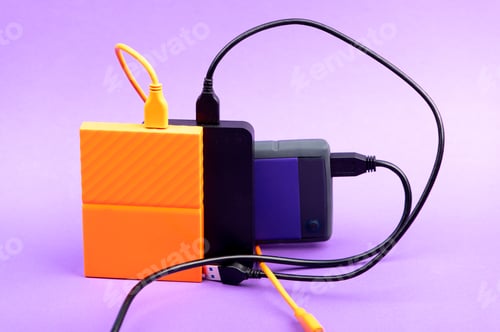 Preview: Multicolored external portable hard disk drives isolated on violet background