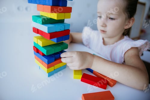 Preview: Child playing with colorful bright wooden bricks on the white table background.