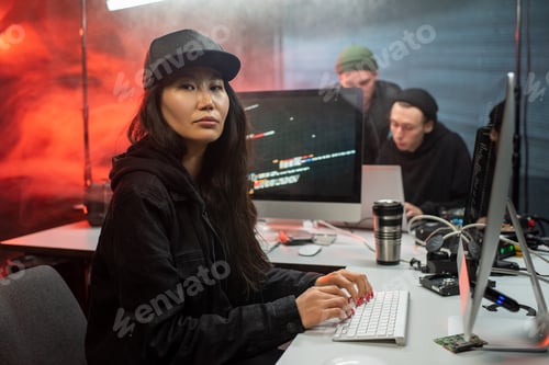 Preview: Serious female hacker sitting in front of computer