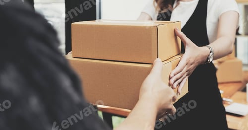 Preview: Closeup female hand accepting a delivery of boxes from deliverywoman.
