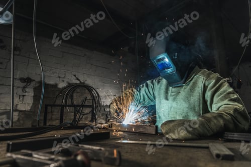 Preview: manual worker in protective helmet with welding torch working in workshop