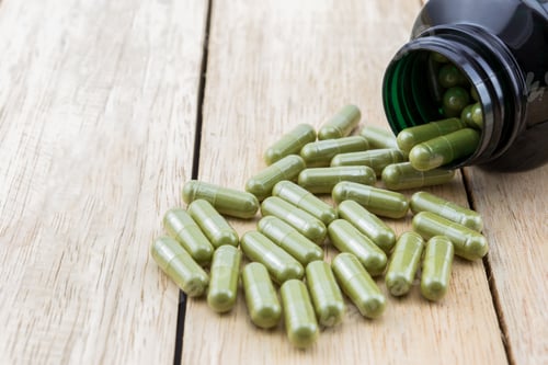 Preview: Herb capsule spilling out of bottle on wooden table