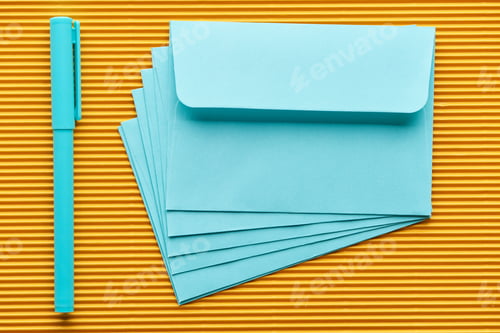 Preview: top view of pen and blue envelopes on yellow