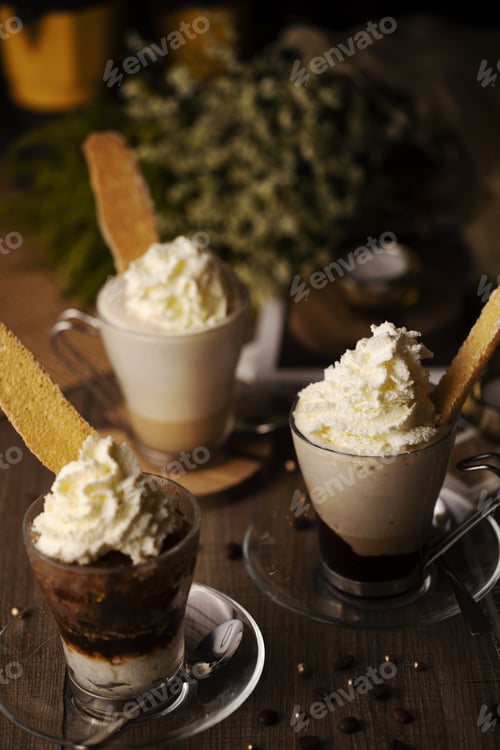 Preview: Vertical shot of three cups of coffee decorated with whipped cream and cookies