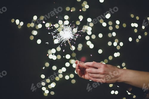 Preview: A young woman holds a sparkler and a gift in her hands. Christmas and New Year. Celebration concept