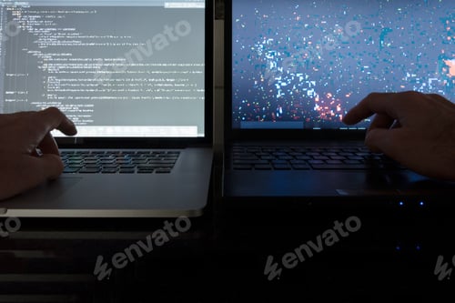 Preview: Dark room working with laptop computer screens hands on keyboards.