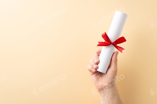 Preview: Closeup of a hand holding a rolled diploma tied with a red ribbon