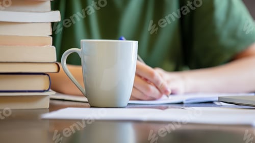 Preview: Woman is writing something in to notebook near coffee cup