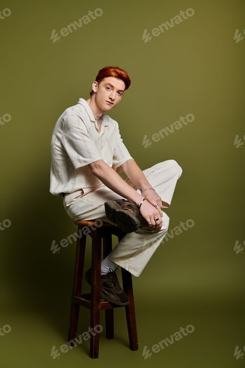 Preview: Emotional moment captured of a young man sitting on a stool against a soft green backdrop
