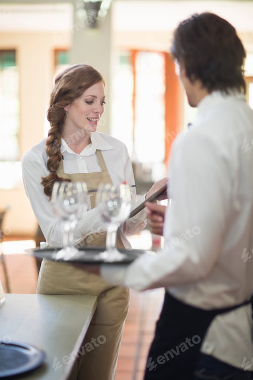 Preview: Waiter and waitress carrying trays of wine glasses in restaurant