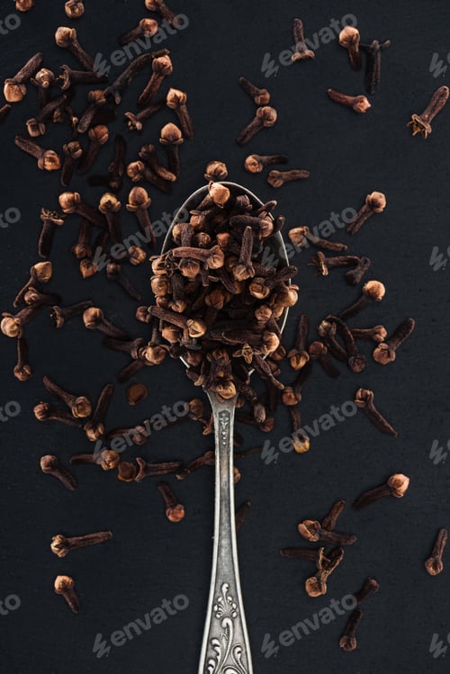Preview: top view of carnation seeds in silver spoon on black background
