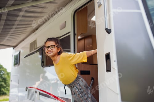 Preview: Happy small girl standing by caravan door, family holiday trip