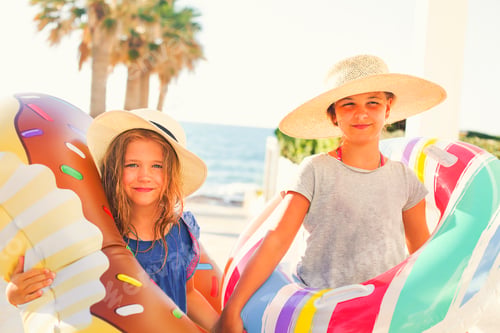 Preview: Two small girls with inflatable toys on the beach