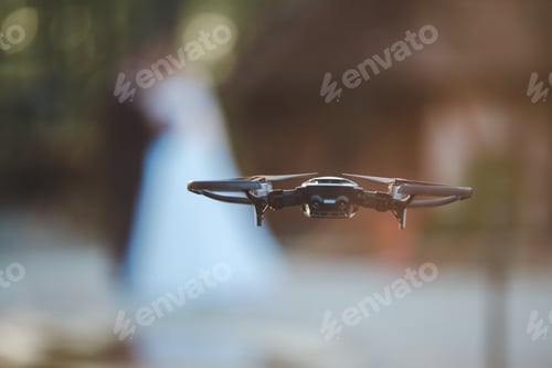 Preview: Closeup of a black drone with a blurred couple in the background