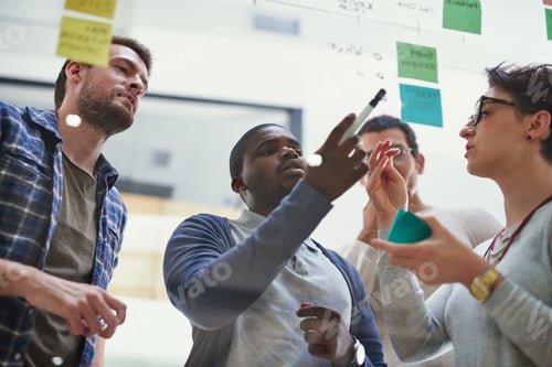 Preview: Shot of a group of designers brainstorming with notes on a glass wall in an office
