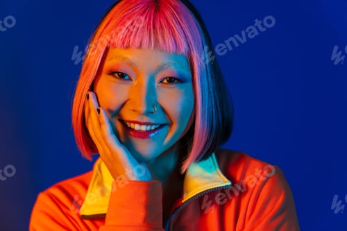 Preview: Asian girl with pink hair and piercing smiling while looking at camera