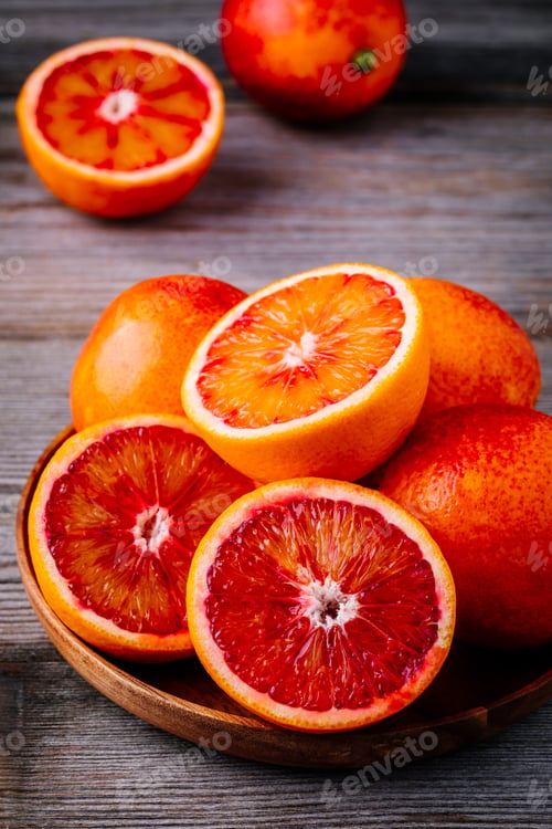Preview: Sliced and whole ripe juicy Sicilian Blood oranges on wooden background.