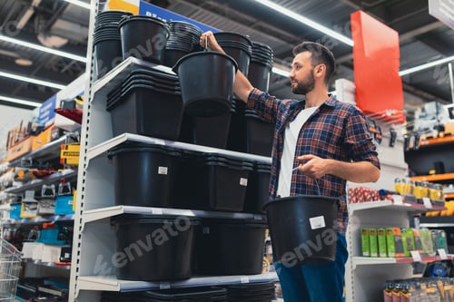 Preview: a man in a hardware store chooses household buckets for repairs in the house.