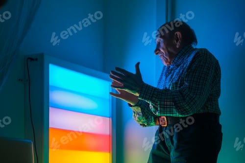 Vista previa: Hombre mayor interactuando con un panel LED multicolor en una sala de juegos sensorial