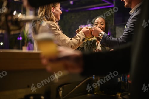 Preview: Cheerful colleagues drinking beer in the bar together after work