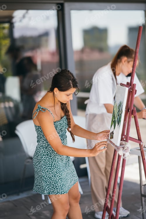 Preview: Young woman artist paints with a spatula on the canvas
