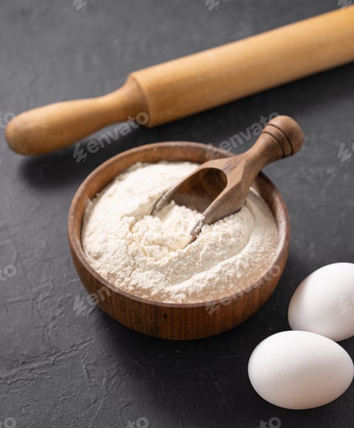 Preview: Organic baking ingredients. Flour, eggs and rolling pin on a dark background close up.
