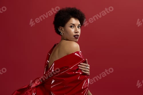 Preview: Captivating young woman exudes style and elegance in striking red attire against a vibrant backdrop