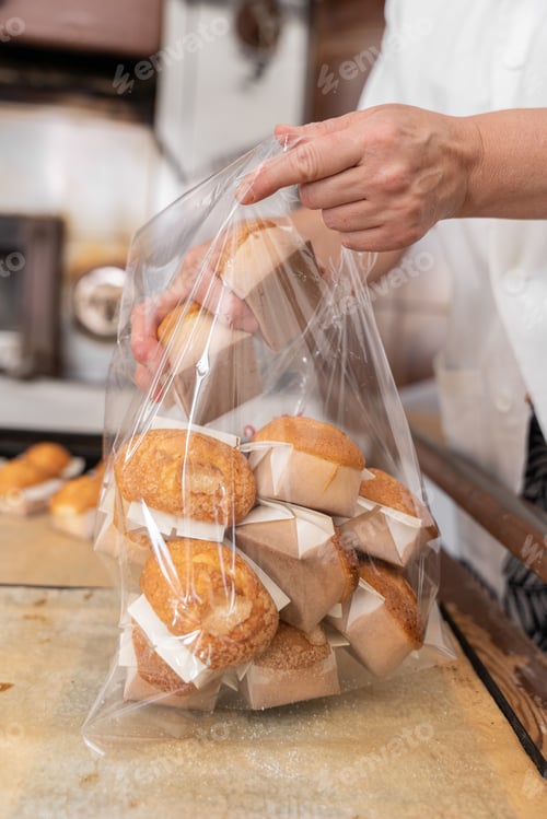 Preview: A baker woman is packing some fresh baked cupcakes into a plastic bag