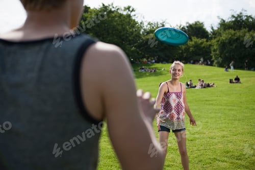 Preview: Germany, Berlin, Teenage girl and boy playing frisbee in park