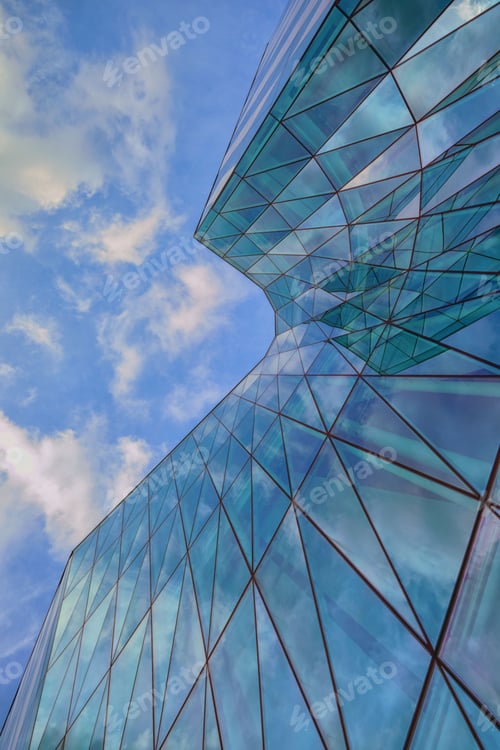 Preview: Low angle shot of an urban glass exterior building with transparent windows under a blue sky