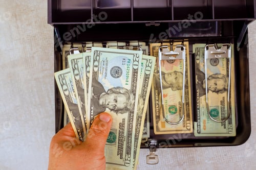 Preview: Hand holding American dollars cash while organizing money in cash box