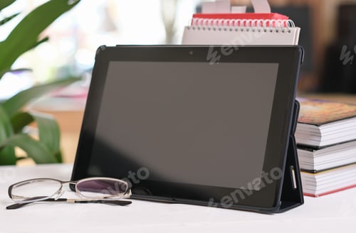 Preview: digital tablet on a desk with eyeglasses and books in a living room. education, home learning