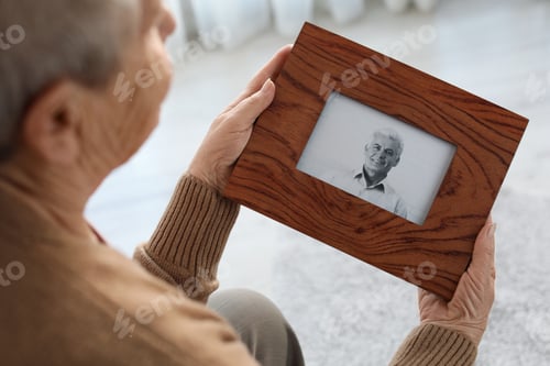 Preview: Elderly woman with framed photo of her son at home